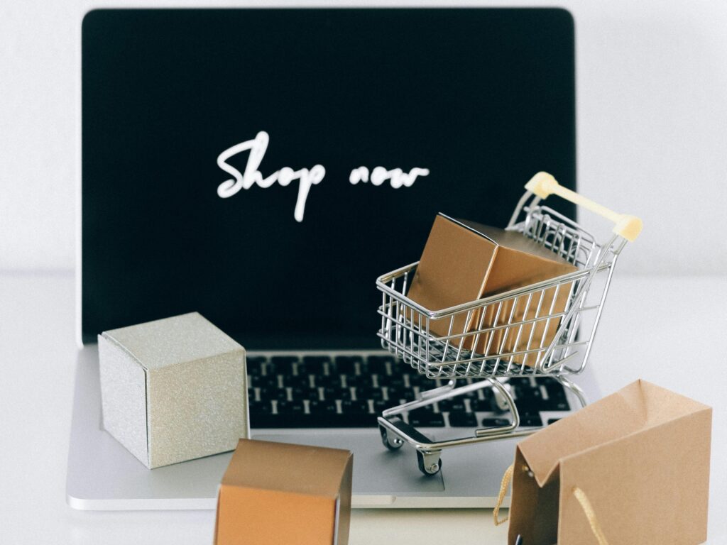 Minimalist online shopping setup with laptop, cart, and packages symbolizing e-commerce.